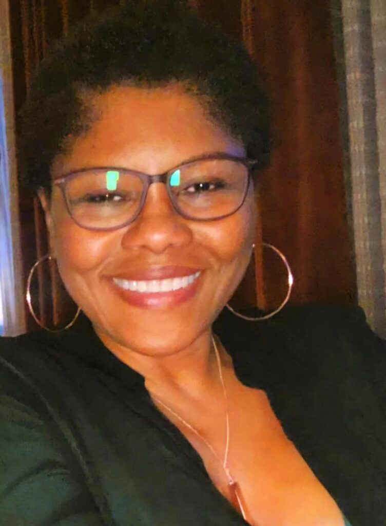 A woman with glasses smiling for the camera.
